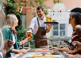 Staff member serving drinks to customers in a pub garden