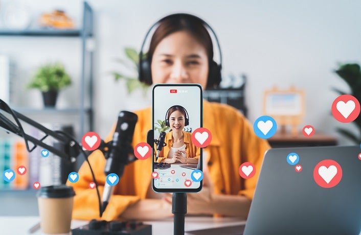 Vlogger live streaming podcast review on social media, Young Asian woman use microphones wear headphones with laptop record video. Content creator concept.