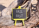 A blackboard sign sitting on a tree that reads 