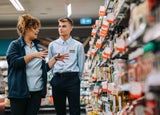 A store supervisor giving training to an employee in the middle of a supermarket aisle.